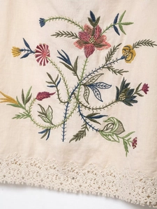Detail of floral embroidery and lace trim on beige cotton linen fabric for women's set