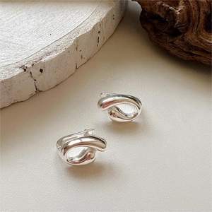 Macro shot of silver minimalist twisted hoop earrings on a textured aesthetic background