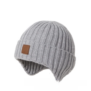 Detail of grey knitted earflap hat showing thick ribbed texture and leather patch
