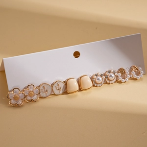 Set of 6 pairs of gold and pearl flower earrings displayed on a white jewelry card