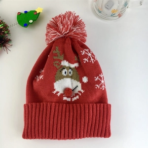 Détail d'un bonnet de Noël rouge tricoté avec motif de renne et nez pompon en 3D