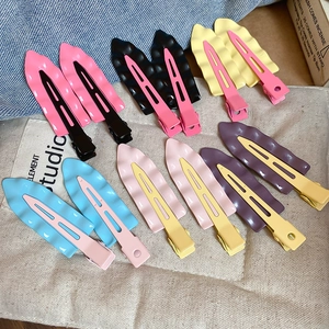Detailed view of matte wavy hairpins in pastel colors like pink and blue on denim cloth