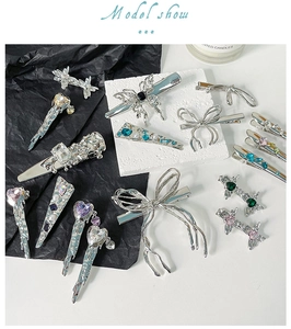 Detail of silver liquid metal bow hair clips with colorful zircons on textured stone