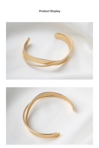 Vista dettagliata del bracciale rigido incrociato oro opaco con design minimalista a doppio anello