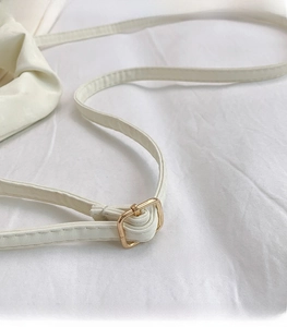 Detail of white leather shoulder strap with adjustable gold square metal buckle buckle