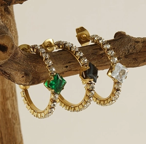 Detailed shot of 18K gold plated earrings with green and black square gemstones on a branch