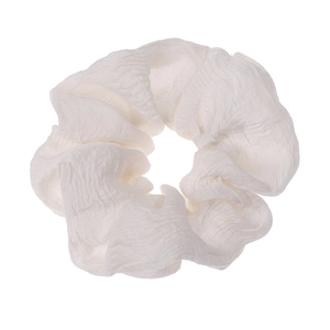 Close-up of white ruffled scrunchie with soft pleated fabric texture on white background