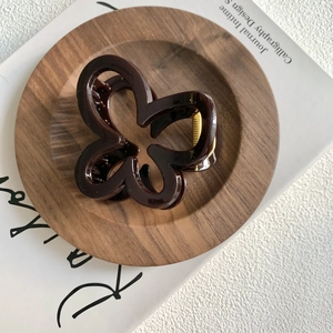 Top view of dark brown butterfly hair claw clip on wooden tray over magazine