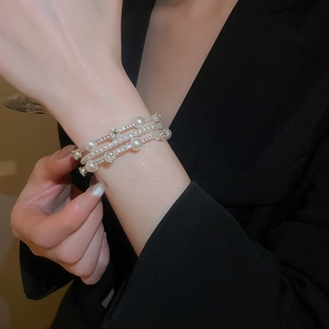 Close-up of layered pearl and rhinestone bracelet on wrist for a luxury elegant look