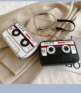 Detail of retro cassette shaped crossbody bags in black and white with gold chain straps