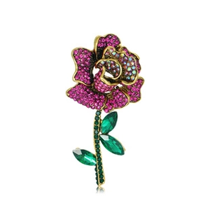 Detail shot of a rose brooch with pink rhinestones and green crystal leaves on a gold base