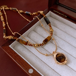 Close-up of double-layered gold necklace with tiger eye stones on jewelry box