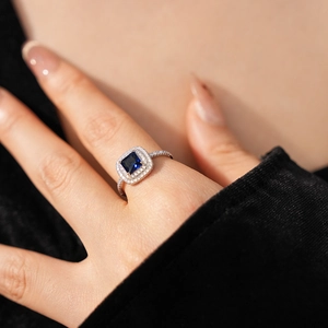 Detail of square blue gemstone ring with halo diamonds on silver-colored band