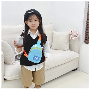 Sac de poitrine enfant en nylon bleu ciel avec sangle orange dans un décor cozy