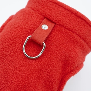 Detail of red fleece dog harness featuring a heavy-duty metal D-ring and reinforced rivets