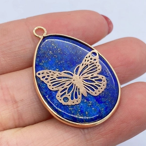 Macro shot of blue lapis lazuli water drop pendant with golden butterfly overlay