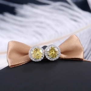 Macro shot of round yellow zircon earrings with white halo on champagne satin ribbon