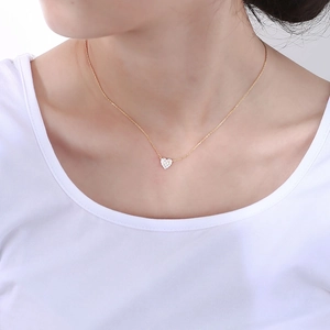 Close-up of a gold S925 heart necklace featuring sparkling cubic zirconia on a model