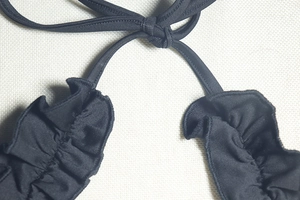 Detailed view of black ruffle hem and adjustable lace-up knot on a backless dress