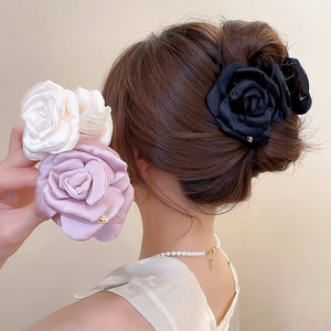 Dettaglio di fermagli per capelli a rosa in raso nei colori nero, rosa e bianco crema
