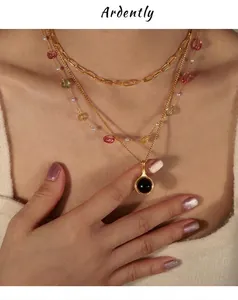 Vue détaillée des colliers superposés plaqués or avec perles colorées et pendentif noir