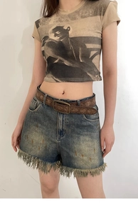Close-up of vintage embossed brown leather belt paired with distressed denim shorts