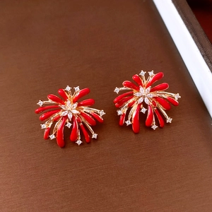 Detailed close-up of red enamel fireworks stud earrings with golden base and white zircons