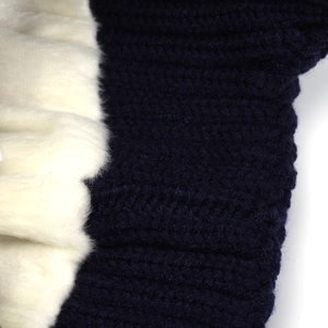 Detailed close-up of dark blue knit texture and soft white faux fur lining on winter hat