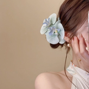 Detail of model wearing orchid hair clip with gradient petals and pearl center decor