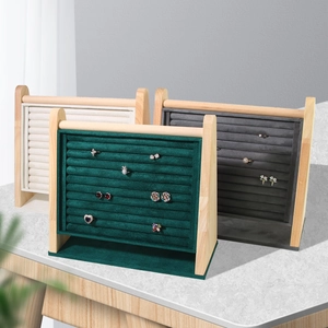 Three wooden ring display stands with velvet inserts in green, gray, and beige colors