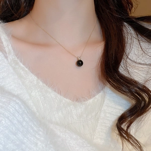 Detailed close-up of a French gold necklace with a black pearl pendant and zircon accents