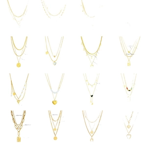 Collection de colliers dorés multicouches avec pendentifs cœur, pièce et perle sur fond blanc