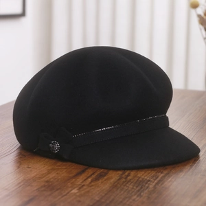 Detail of elegant black wool newsboy hat featuring a stylish bow and rhinestone buckle