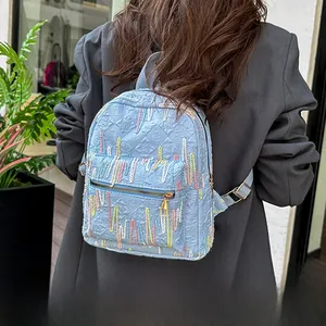 Close-up of light blue PU backpack featuring embroidered texture and golden zipper detail