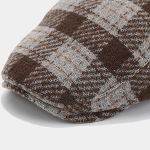 Close-up of the thick brown plaid wool fabric and texture of the retro flat cap
