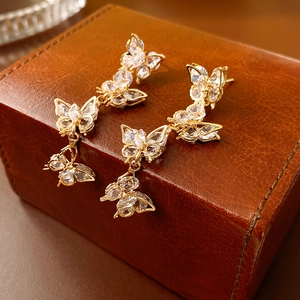 Close-up of long butterfly drop earrings with gold zircons on a leather jewelry box