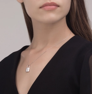 Macro shot of minimalist S925 sterling silver padlock pendant necklace on model neck
