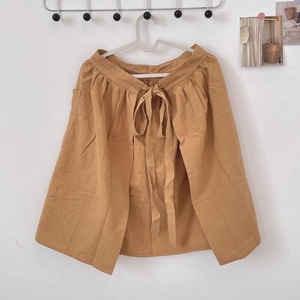 Detail showing the pleated waist and tie-up design of this ginger yellow cotton apron