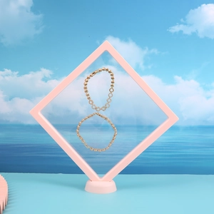 Golden link bracelet suspended in a pink floating display box with ocean sky background