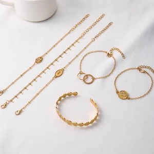 Detailed set of five gold plated bracelets featuring shell, coin charms and textured bangle