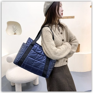 Navy blue quilted puffer tote bag shown on a model in a minimalist modern interior