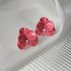 Macro shot of 14K gold-plated floral earrings with pink petals and a crystal center