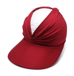 Detail of red sun visor with wide brim, top knot design and reinforced stitching texture