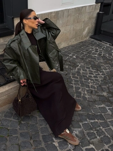 Outdoor street style shot of a dark green oversized leather jacket with a long skirt