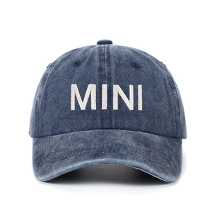 Detailed view of MINI embroidered lettering on navy blue washed denim baseball cap