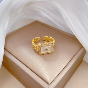 Adjustable gold watch-shaped ring with zircon stones on a white silk background