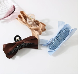 Close-up of large satin bow hair claws in champagne, brown and light blue colors