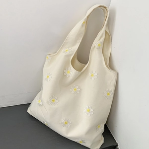 Detail of white canvas tote bag with yellow and white daisy floral embroidery