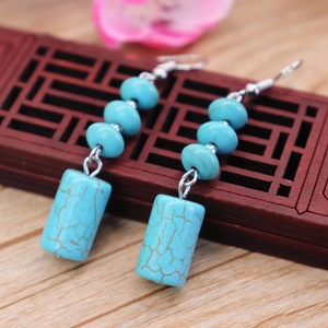 Macro shot of ethnic style turquoise water-drop earrings on a vintage wooden carved base