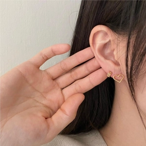 Elegant 925 sterling silver heart earrings and small gold hoop on model's ear